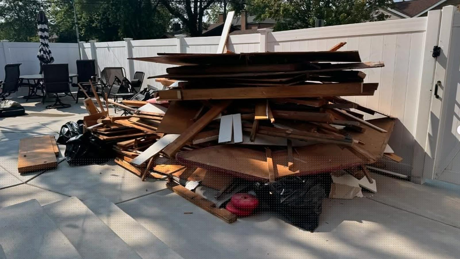 A large pile of construction debris and lumber stacked in a driveway ready for hauling