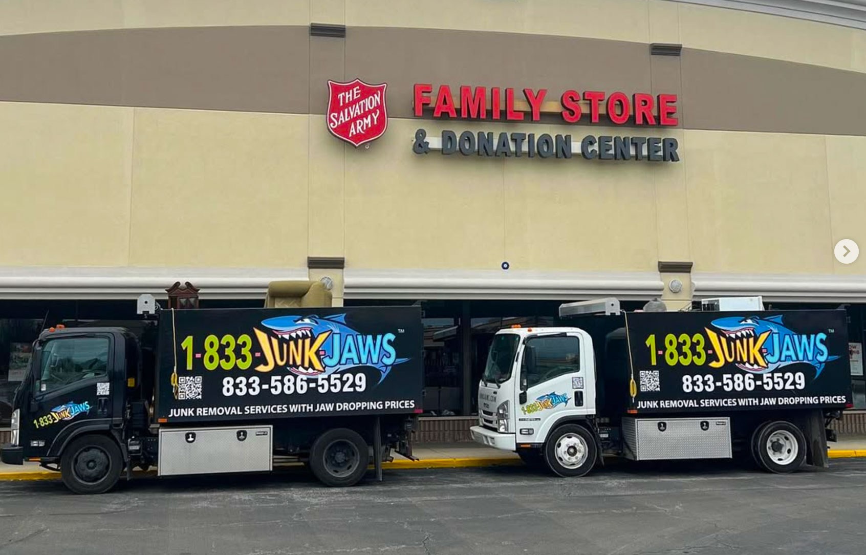Two Junk Jaws trucks unloading usable items at a Salvation Army family store donation center